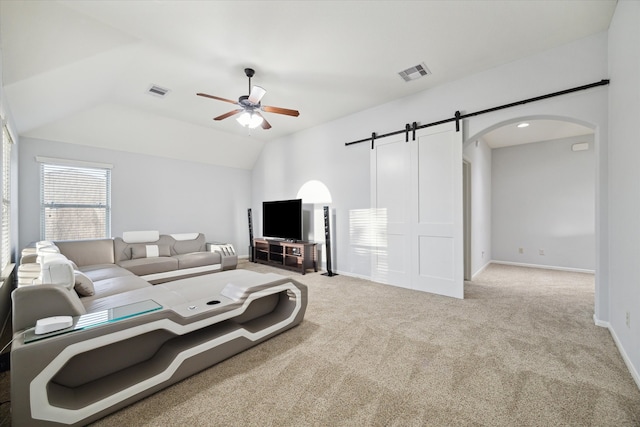 living room featuring light carpet, a barn door, ceiling fan, and vaulted ceiling