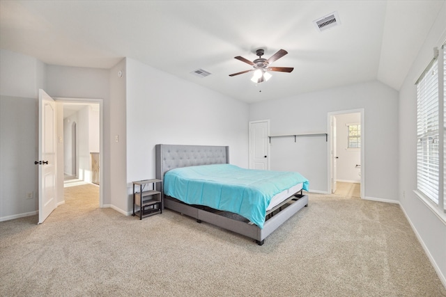 carpeted bedroom with ensuite bathroom, ceiling fan, and lofted ceiling