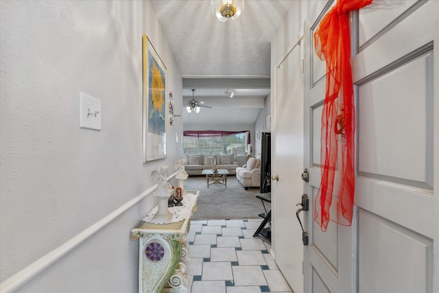 entrance foyer with light carpet, beamed ceiling, a textured ceiling, and a ceiling fan