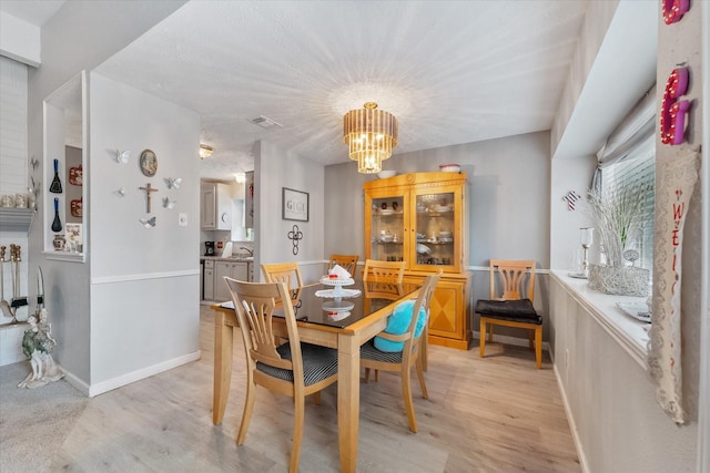 dining space with a notable chandelier, visible vents, light wood-style flooring, and baseboards