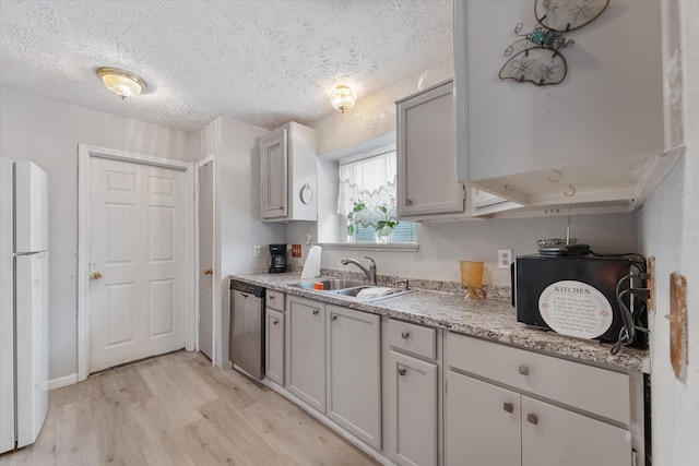 kitchen featuring light wood-type flooring, a sink, freestanding refrigerator, light countertops, and dishwasher