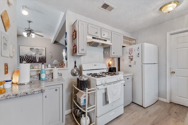 kitchen with under cabinet range hood, visible vents, white appliances, and light wood-style floors