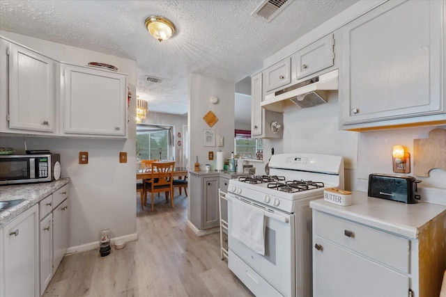 kitchen featuring stainless steel microwave, visible vents, white gas stove, under cabinet range hood, and light countertops