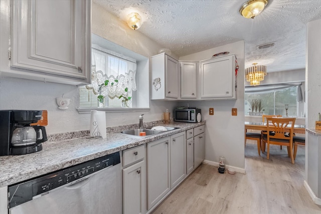 kitchen featuring visible vents, stainless steel appliances, light wood-style floors, a textured ceiling, and a sink