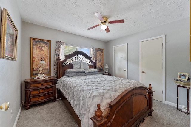 bedroom with light colored carpet, baseboards, and a textured ceiling