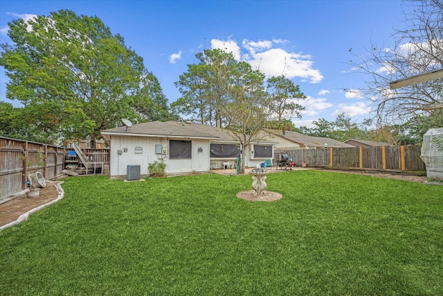 rear view of house featuring a lawn, central AC, and a fenced backyard