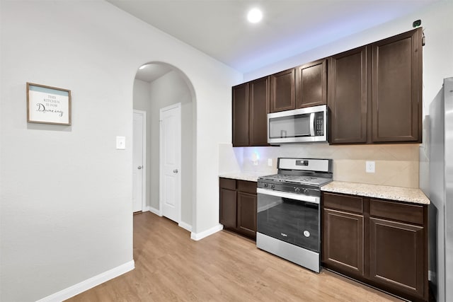 kitchen featuring appliances with stainless steel finishes, decorative backsplash, dark brown cabinetry, and light hardwood / wood-style floors