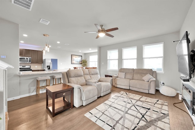 living room with light hardwood / wood-style floors, a healthy amount of sunlight, and ceiling fan