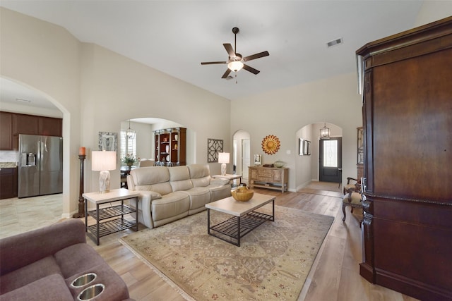 living room with a healthy amount of sunlight, light wood-type flooring, and high vaulted ceiling