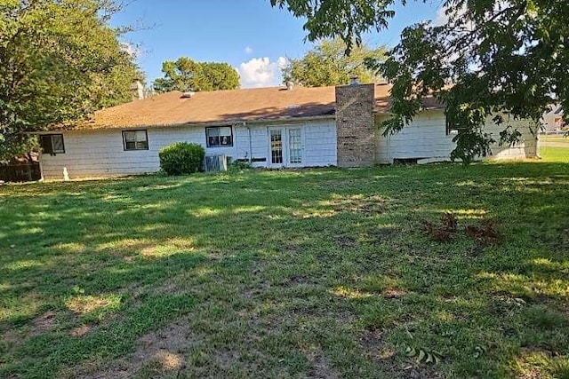 back of house featuring central AC unit, a lawn, and french doors