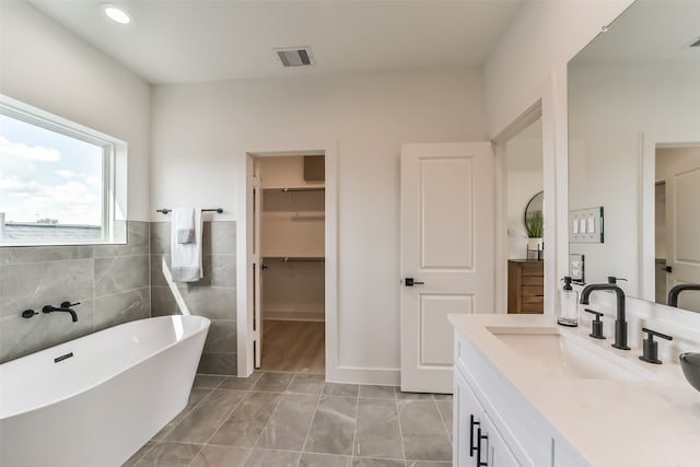 bathroom featuring tile walls, vanity, and a tub