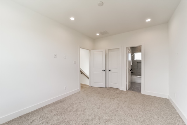 unfurnished bedroom featuring connected bathroom and light carpet