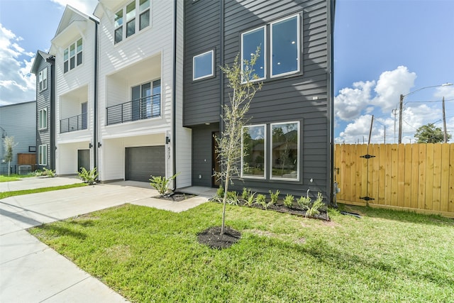 view of front of home featuring a balcony, a garage, and a front yard