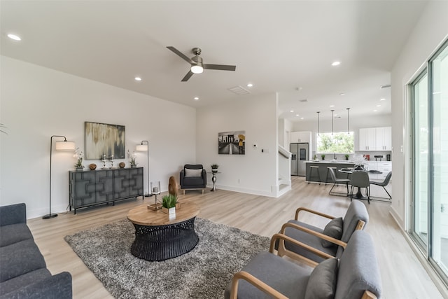 living room featuring light hardwood / wood-style floors, ceiling fan, and sink