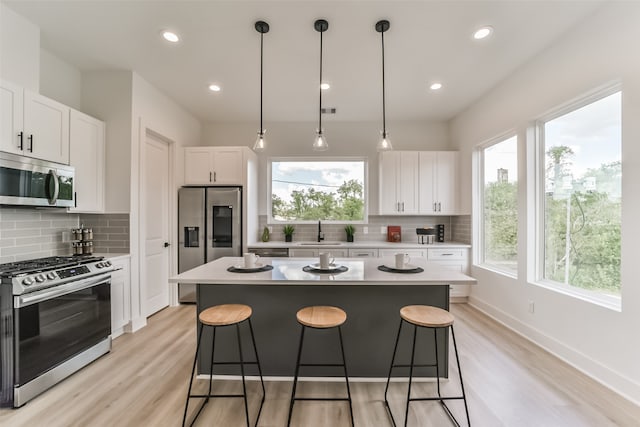 kitchen with light wood-type flooring, white cabinetry, a center island, and stainless steel appliances