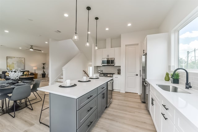 kitchen with hanging light fixtures, sink, gray cabinets, white cabinetry, and appliances with stainless steel finishes