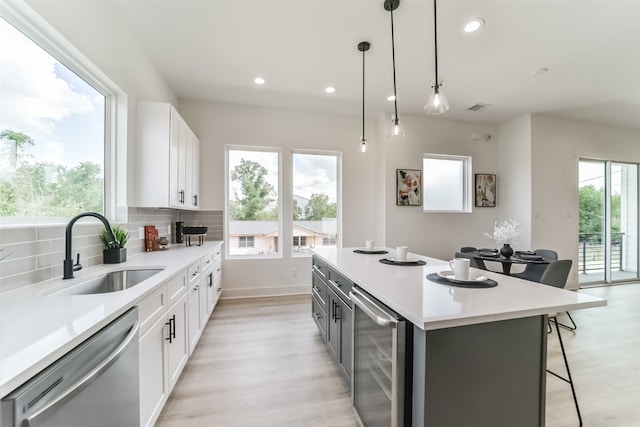 kitchen featuring white cabinets, tasteful backsplash, stainless steel dishwasher, pendant lighting, and wine cooler