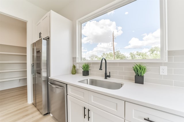 kitchen with stainless steel appliances, white cabinets, sink, and plenty of natural light