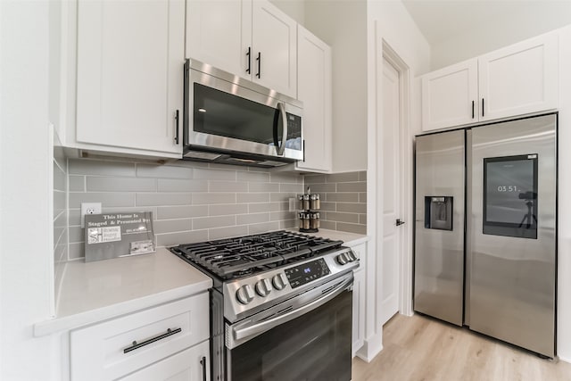 kitchen with white cabinetry, stainless steel appliances, light hardwood / wood-style floors, and tasteful backsplash