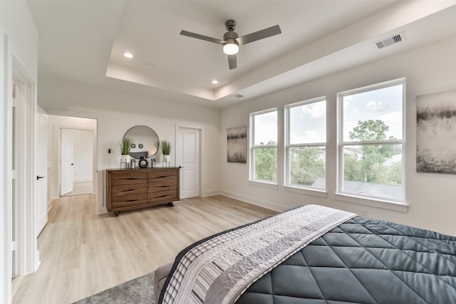 bedroom with ceiling fan, a raised ceiling, and light hardwood / wood-style flooring