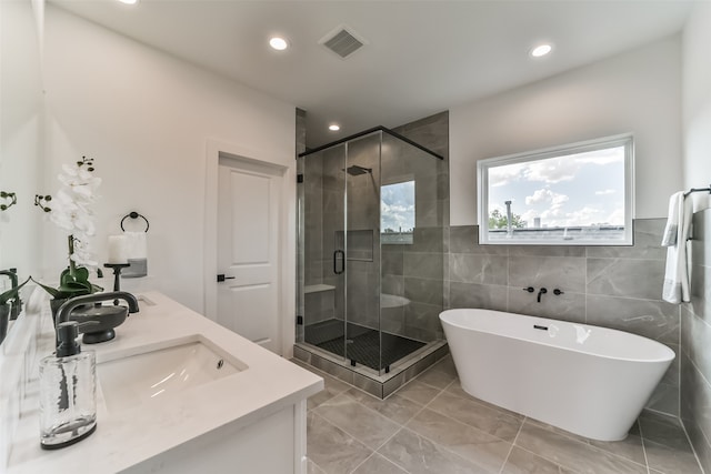 bathroom featuring tile walls, vanity, and shower with separate bathtub