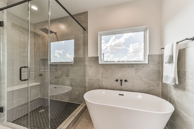 bathroom featuring independent shower and bath, tile patterned flooring, and tile walls