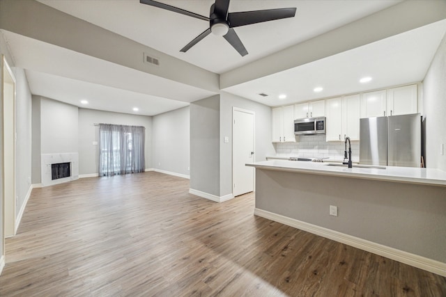 kitchen with a fireplace, white cabinets, light hardwood / wood-style floors, and stainless steel appliances