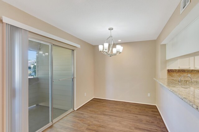 unfurnished dining area with light wood-type flooring and an inviting chandelier