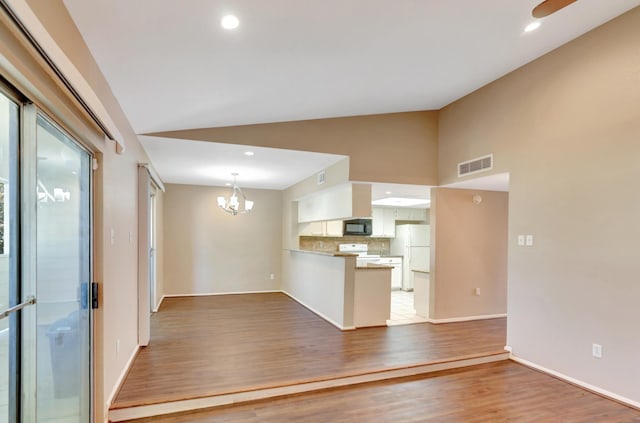 unfurnished living room with hardwood / wood-style flooring, lofted ceiling, and an inviting chandelier