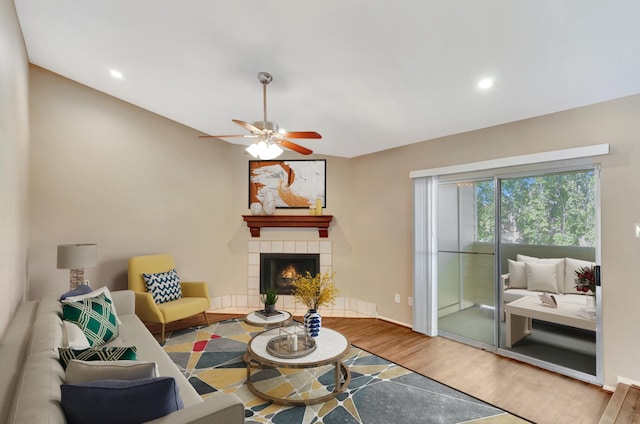 living room featuring a tiled fireplace, ceiling fan, wood-type flooring, and vaulted ceiling