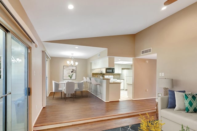 living room with visible vents, baseboards, a chandelier, lofted ceiling, and light wood-style flooring