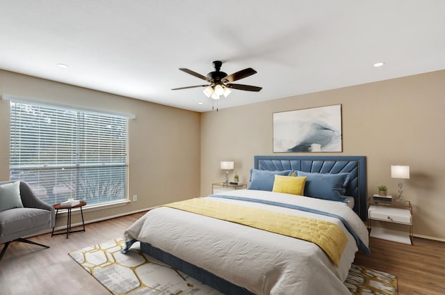 bedroom featuring hardwood / wood-style floors, ceiling fan, and multiple windows