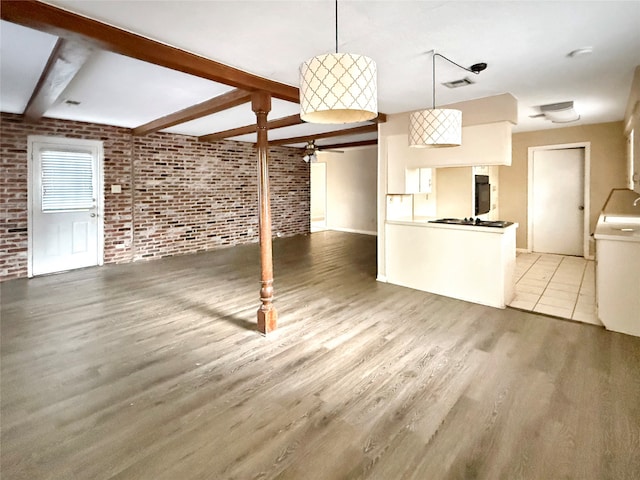 unfurnished living room with beamed ceiling, light wood-type flooring, and brick wall