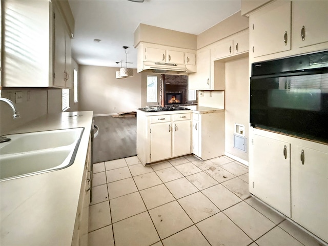 kitchen with sink, black appliances, light tile patterned floors, white cabinets, and pendant lighting