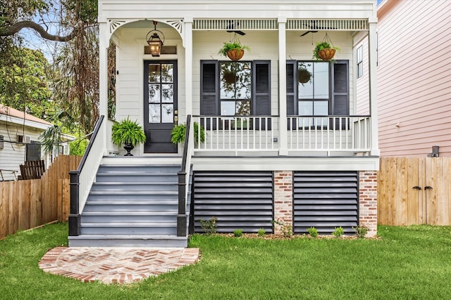 view of exterior entry with a yard and covered porch