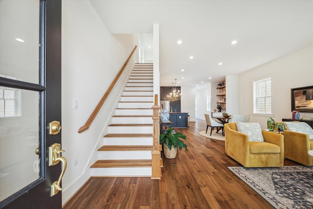 stairway with hardwood / wood-style floors and a notable chandelier