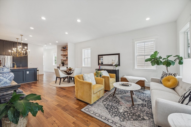 living room with light wood-type flooring, a chandelier, and sink