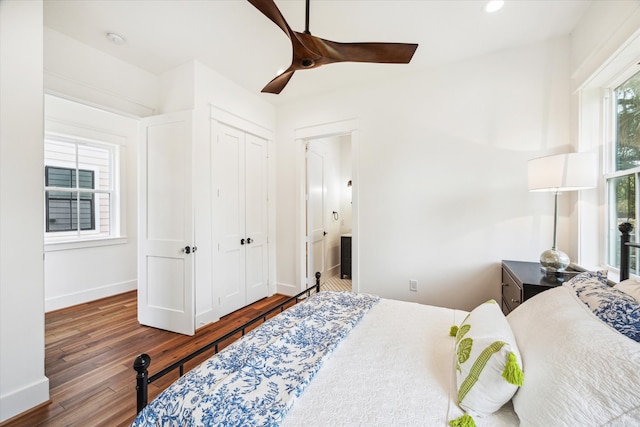 bedroom with connected bathroom, dark wood-type flooring, ceiling fan, and a closet