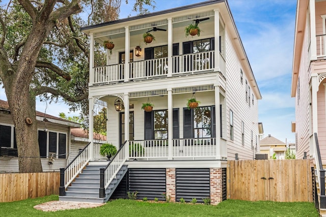 view of front of house featuring a front lawn, covered porch, ceiling fan, and a balcony