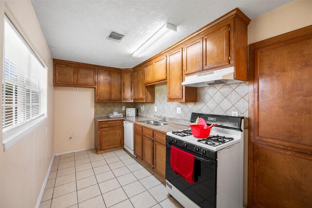 kitchen featuring tasteful backsplash, sink, light tile patterned floors, and white appliances