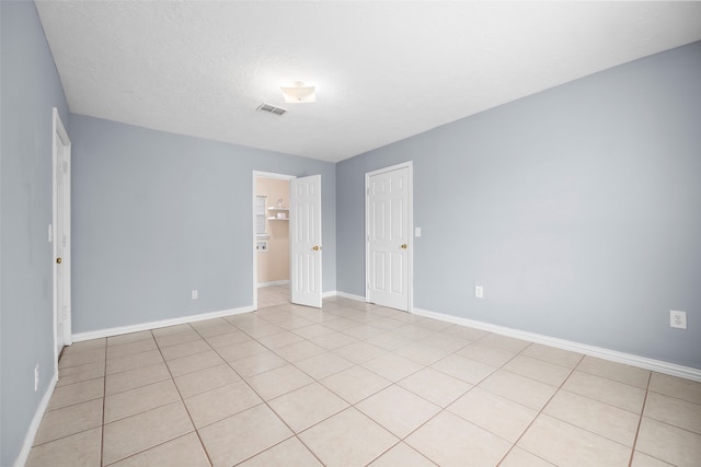 empty room featuring light tile patterned floors and a textured ceiling