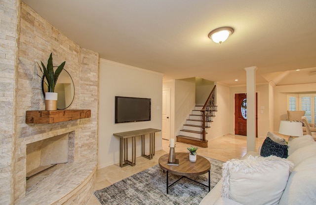 living room featuring a fireplace, crown molding, and decorative columns