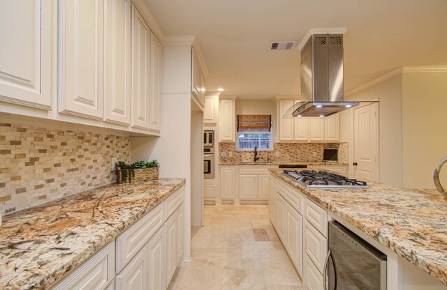 kitchen featuring island exhaust hood, light stone counters, crown molding, backsplash, and appliances with stainless steel finishes