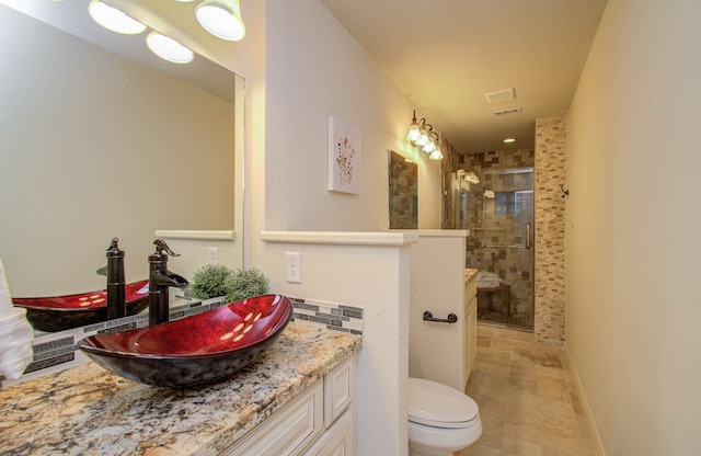 bathroom featuring tiled shower, toilet, and vanity