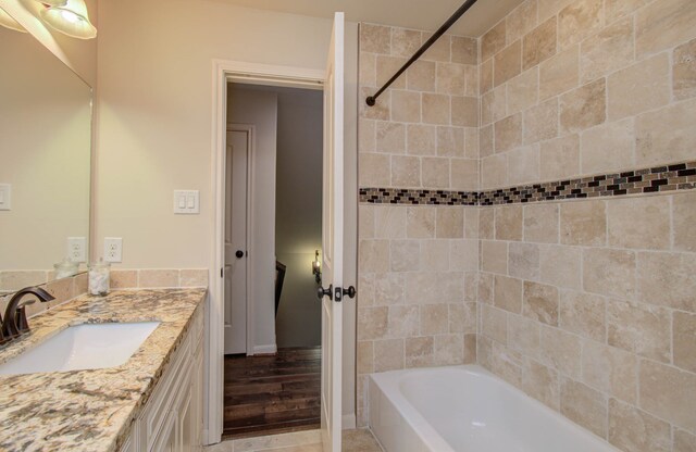 bathroom featuring wood-type flooring, vanity, and tiled shower / bath combo