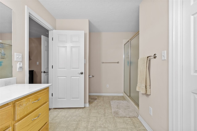 bathroom featuring walk in shower, vanity, and a textured ceiling