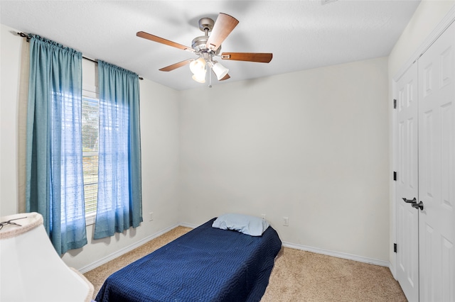 bedroom with ceiling fan, light carpet, and a closet