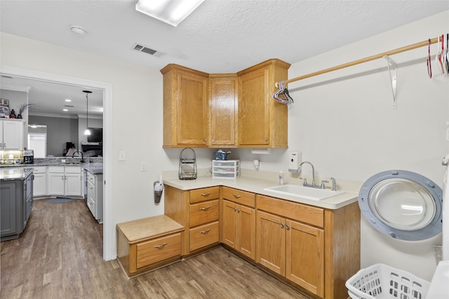 kitchen with kitchen peninsula, hardwood / wood-style floors, a textured ceiling, sink, and washer / clothes dryer