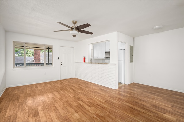 unfurnished living room with wood-type flooring, a textured ceiling, electric panel, and ceiling fan