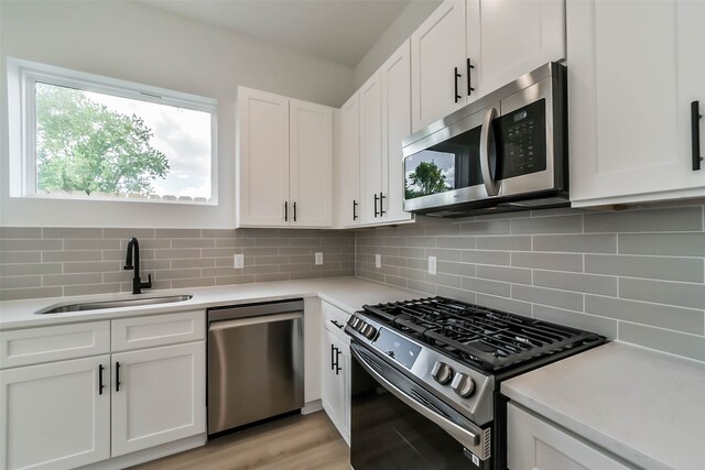 kitchen with white cabinetry, sink, backsplash, and stainless steel appliances